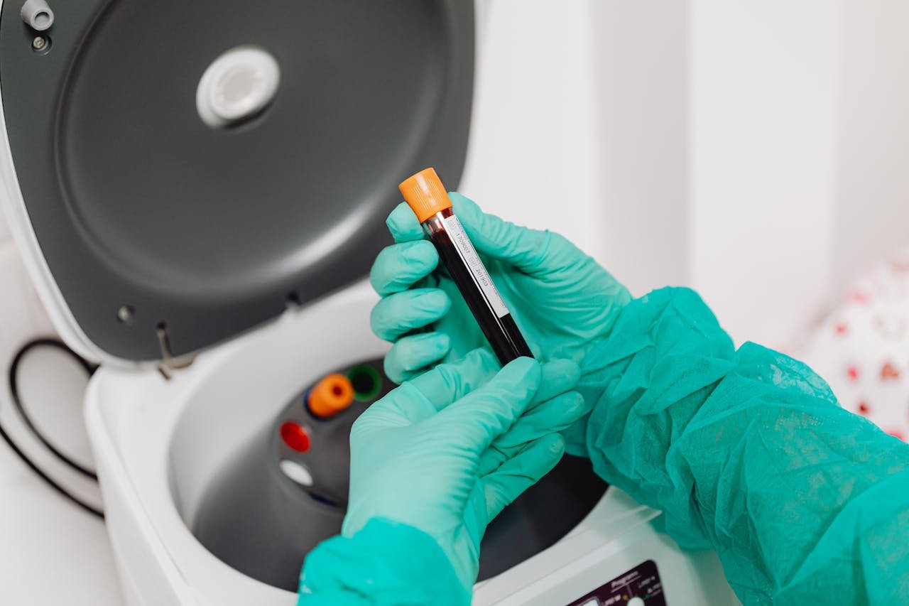 Laboratory scene with a healthcare professional preparing a blood sample for analysis using a centrifuge.